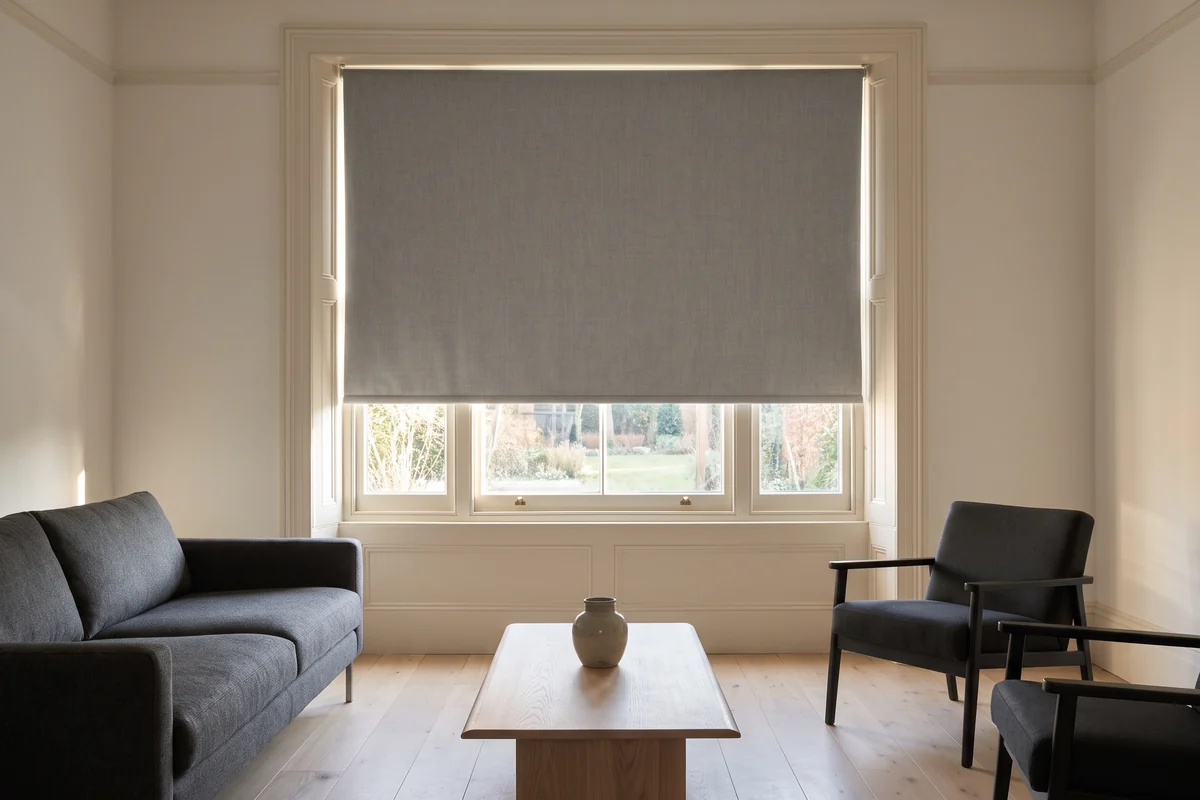 A wide living room window with a single roller blind spanning the opening