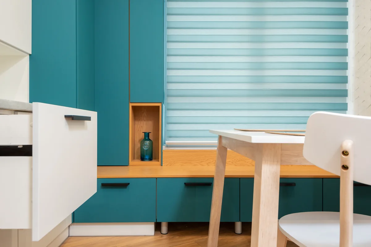 A roller blind lowered over a kitchen window above a bench