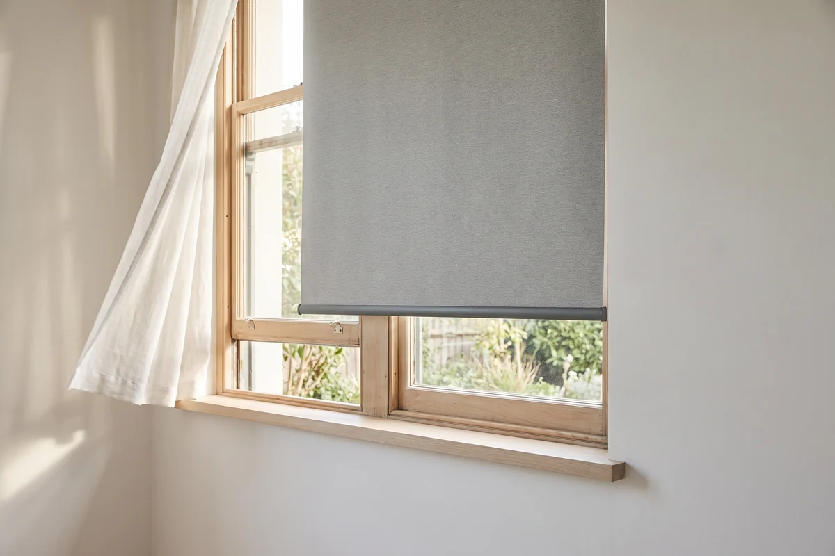 A blind hanging at an open window with the bottom rail free to swing