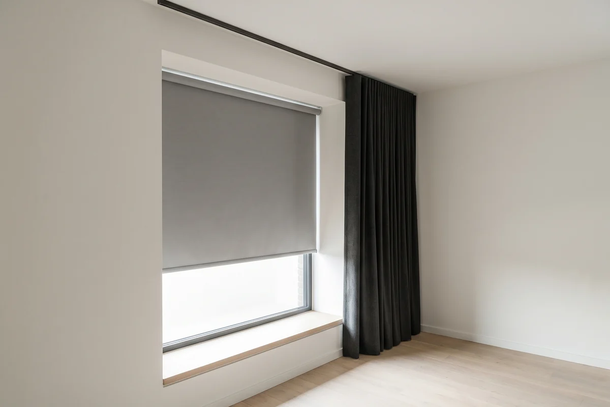 One window with two systems: a roller blind inside the reveal and a curtain on a track mounted forward on the wall