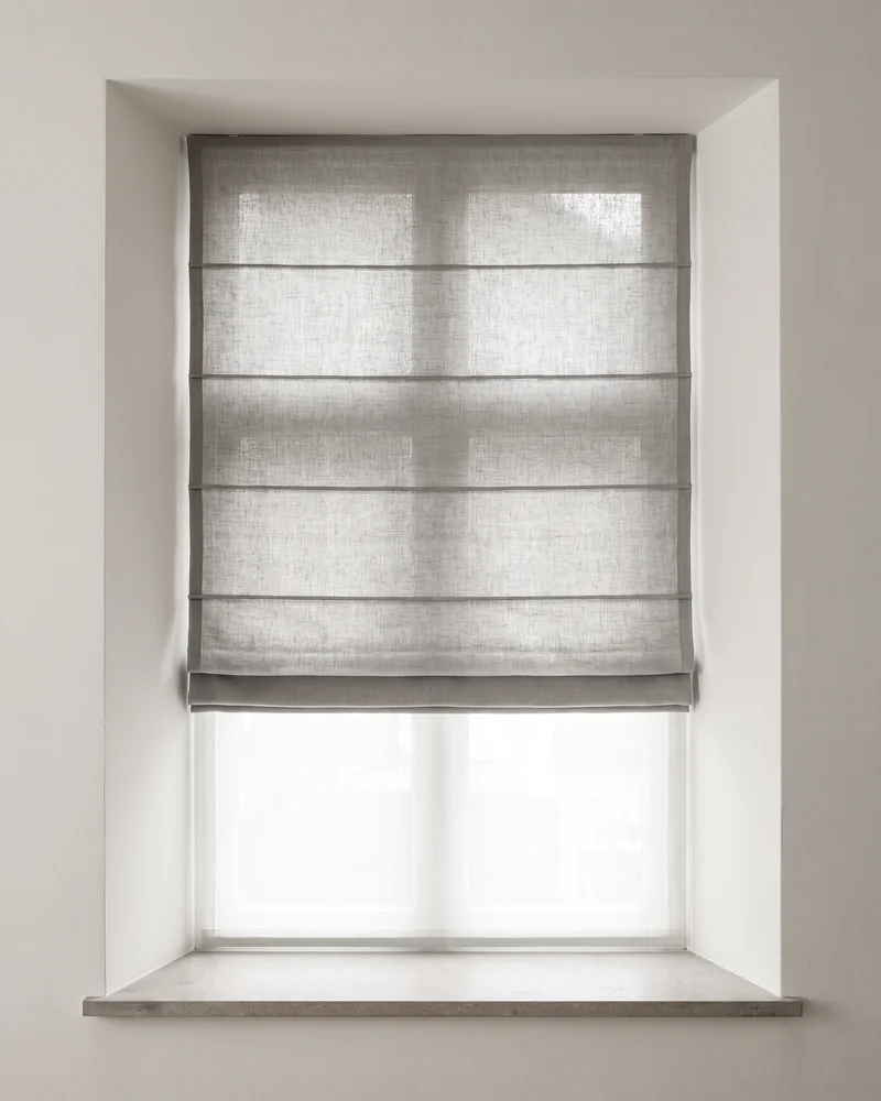 A Roman blind in soft folds at a living-room window