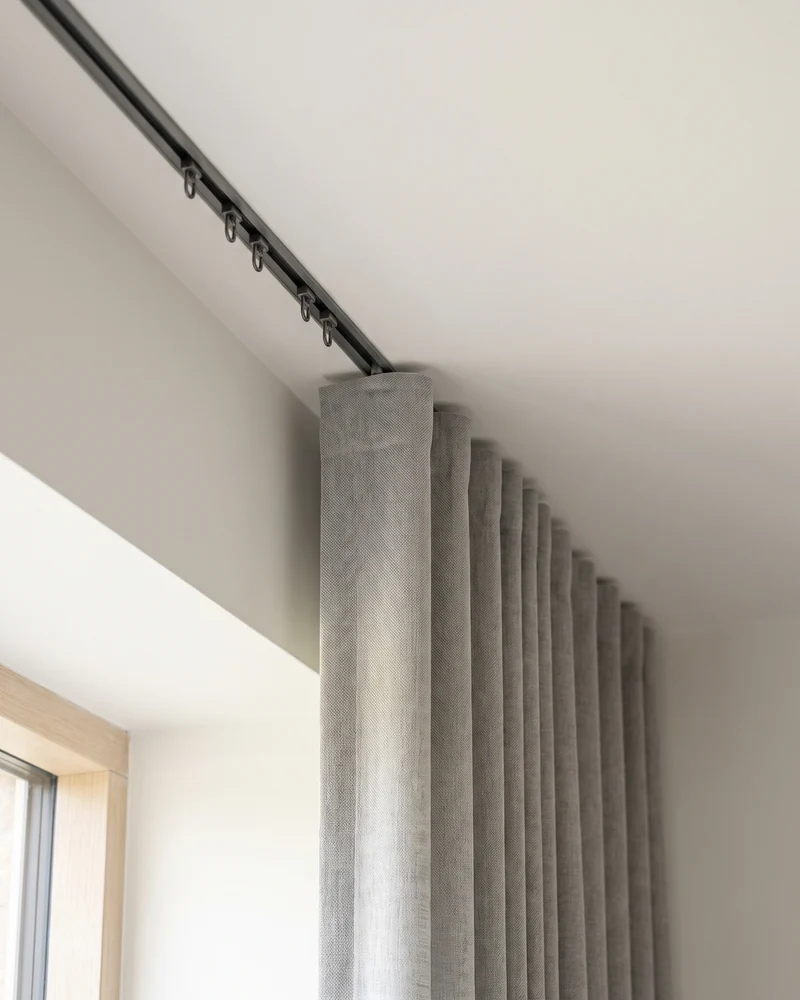The top of an S fold curtain meeting a slim track recessed flush into the ceiling