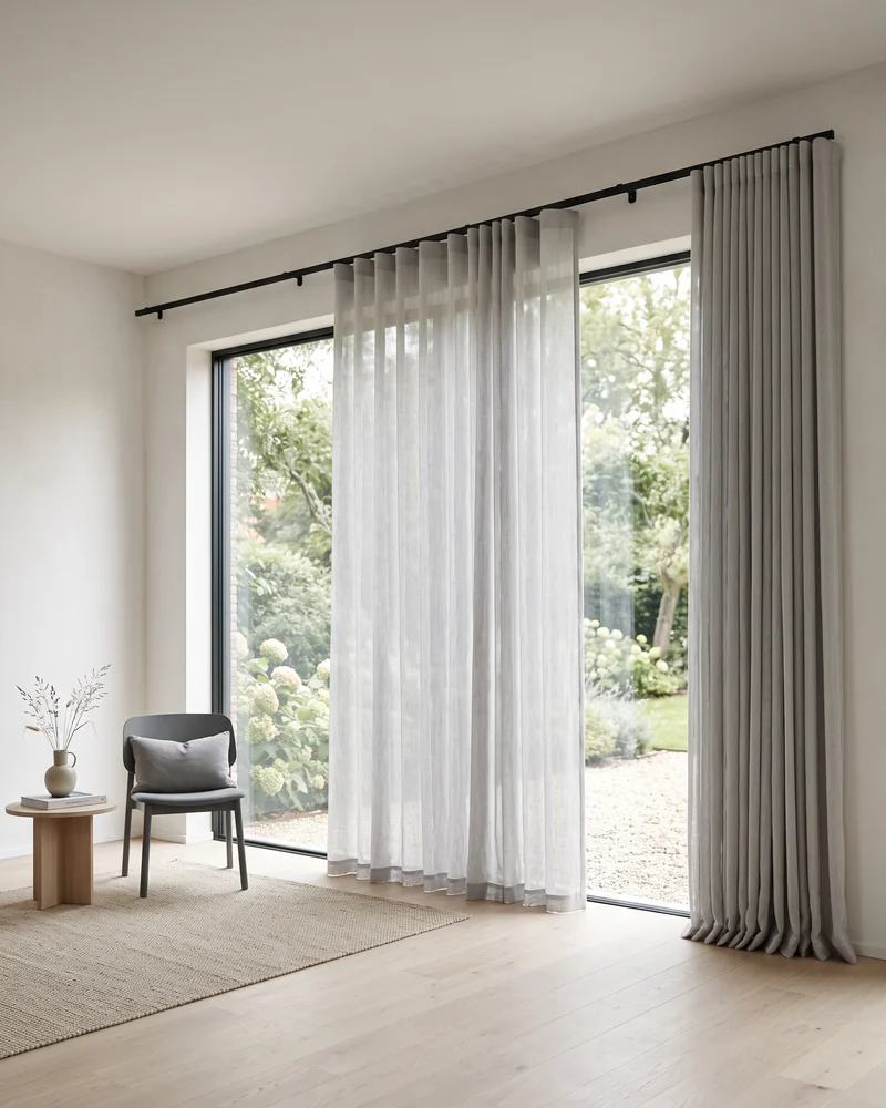 A sheer S fold curtain drawn across a wide sliding glass door with the track running past the opening