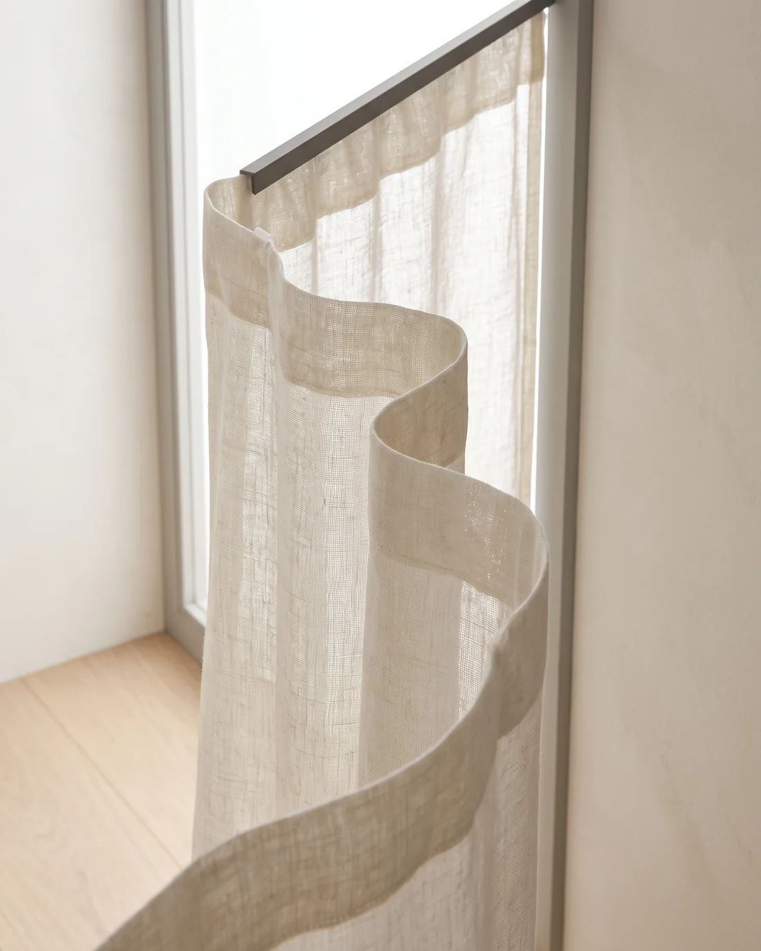 Detail of a sheer S fold curtain curving forward and back in an even wave below its ceiling track