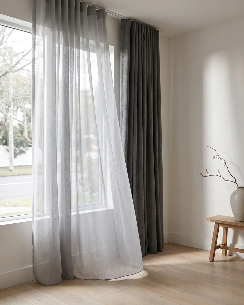 A sheer curtain layered in front of a blockout curtain on a double track