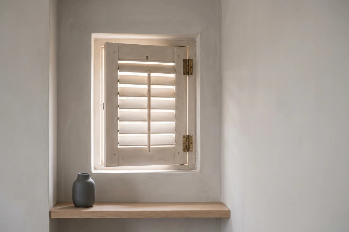 A single louvred shutter panel hinged into a small square window