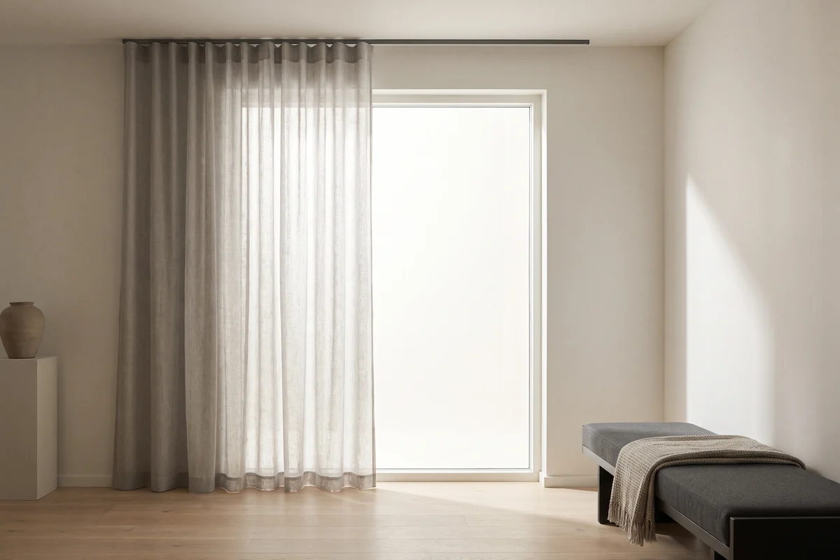 A single sheer curtain hanging alone at a bright window