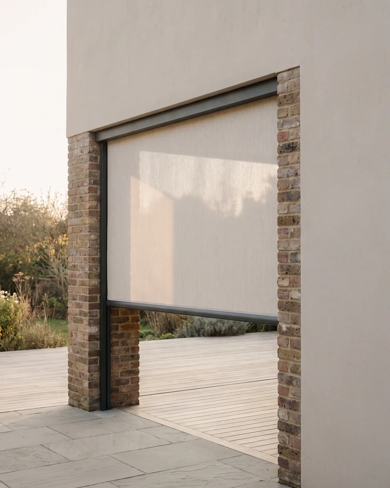 A straight-drop outdoor blind lowered across a patio opening