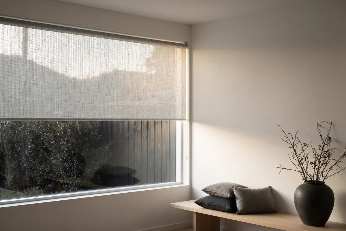 A street-facing living room window with a sunscreen blind lowered for daytime privacy