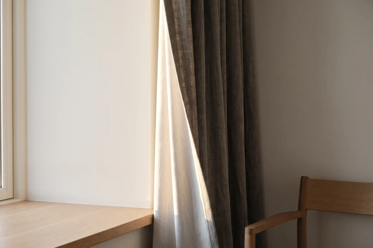 Late afternoon sun striking the leading edge of a lined curtain at a west-facing window