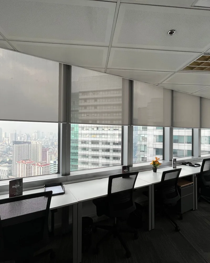 Sunscreen roller blinds half lowered across a wall of glazing