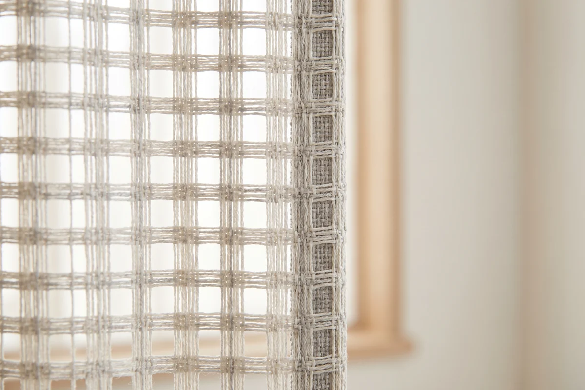 The open weave of a sunscreen blind fabric seen close up against daylight
