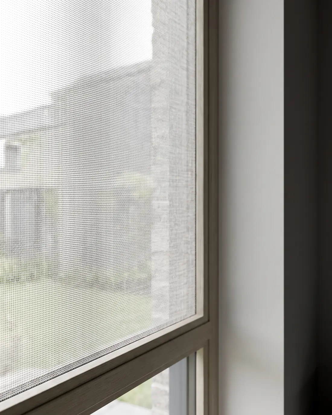 Sunscreen roller blind fabric backlit at a window, the open weave clearly visible