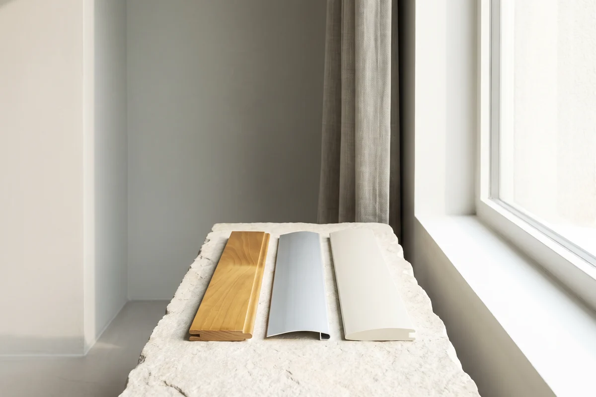 Timber, aluminium and PVC venetian slats laid side by side in daylight