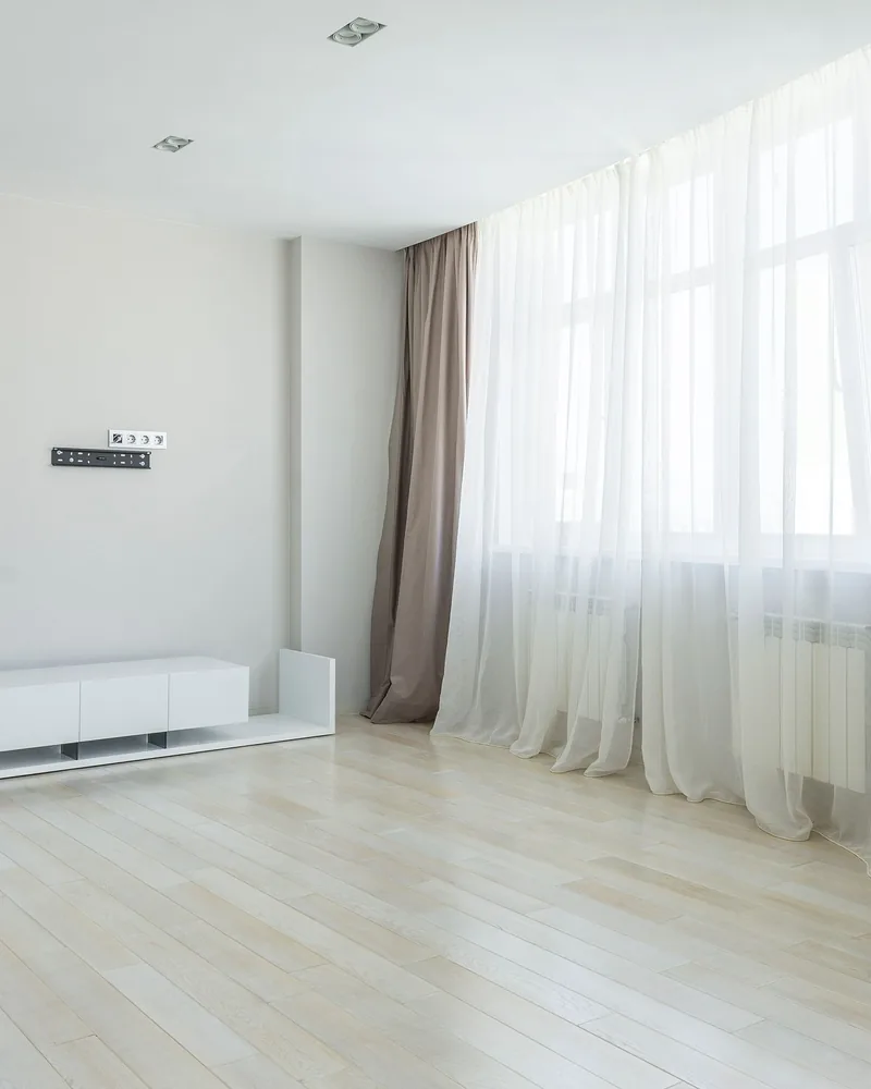 Long curtains over a timber floor in a light-filled living room