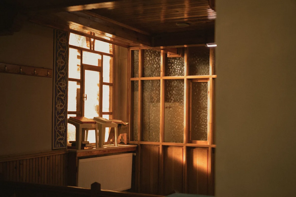 Late afternoon sun through the sash window of a timber-lined room