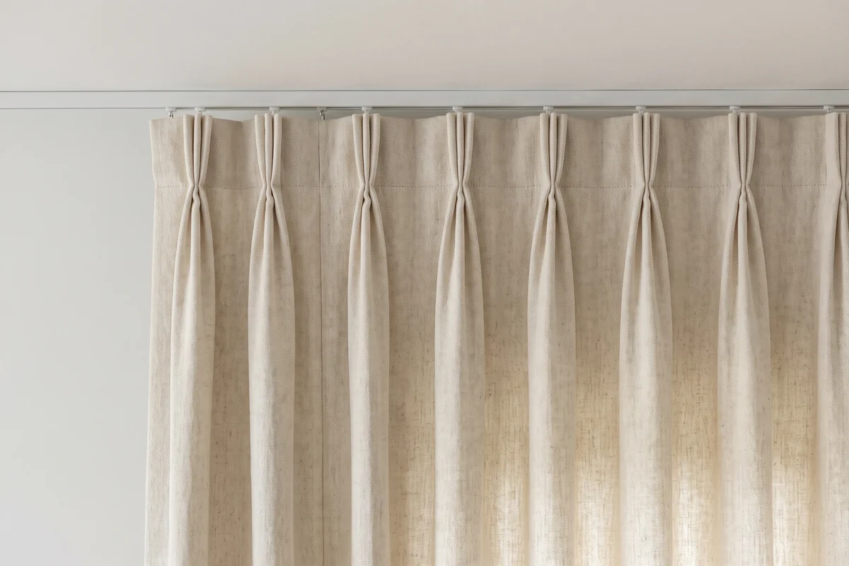 A triple pinch pleat curtain heading, fabric stitched into groups of three folds and hooked onto a ceiling track