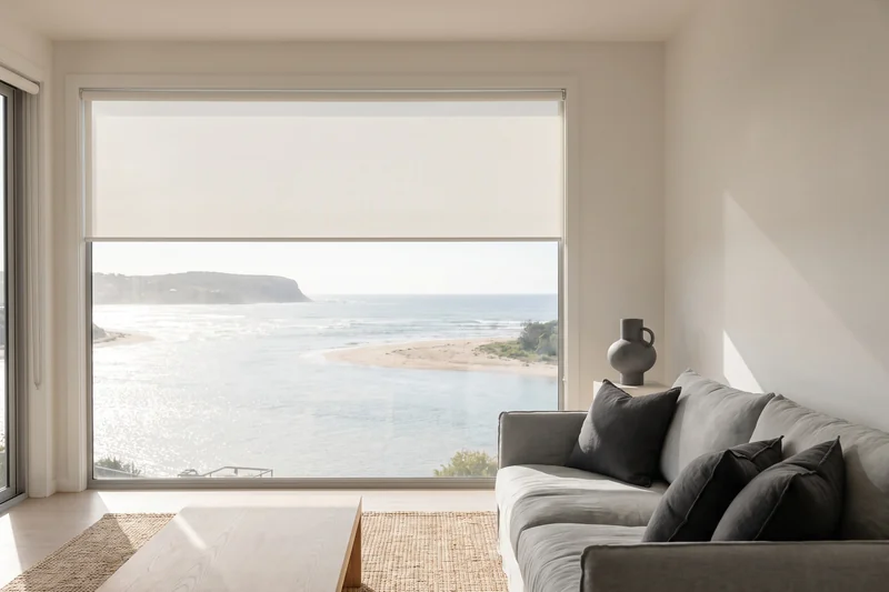 Sunscreen blind half lowered across wide glass looking over a river mouth to the sea