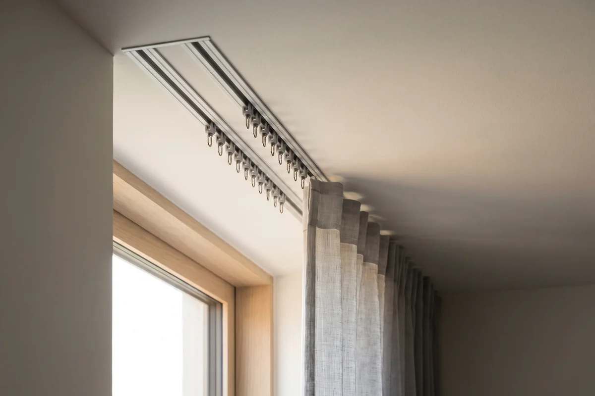 A double curtain track with two channels of runners fixed to a ceiling
