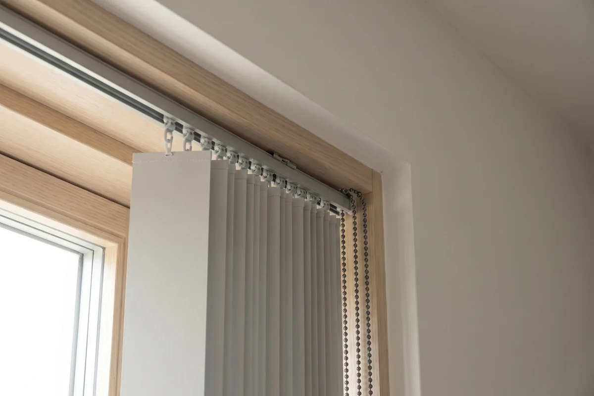 The headrail of a vertical blind with its carriers visible
