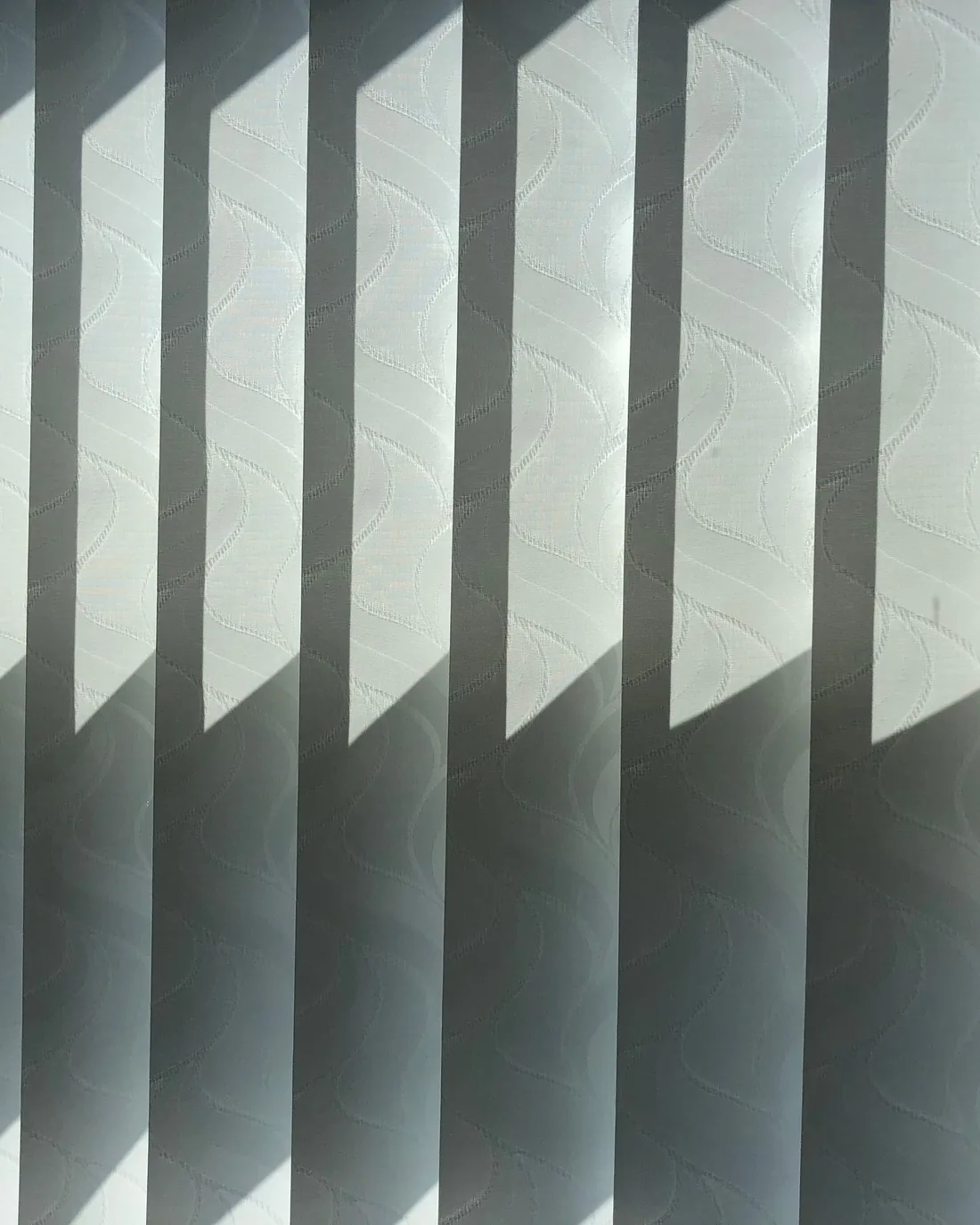 Close detail of a white fabric blind at a window in daylight
