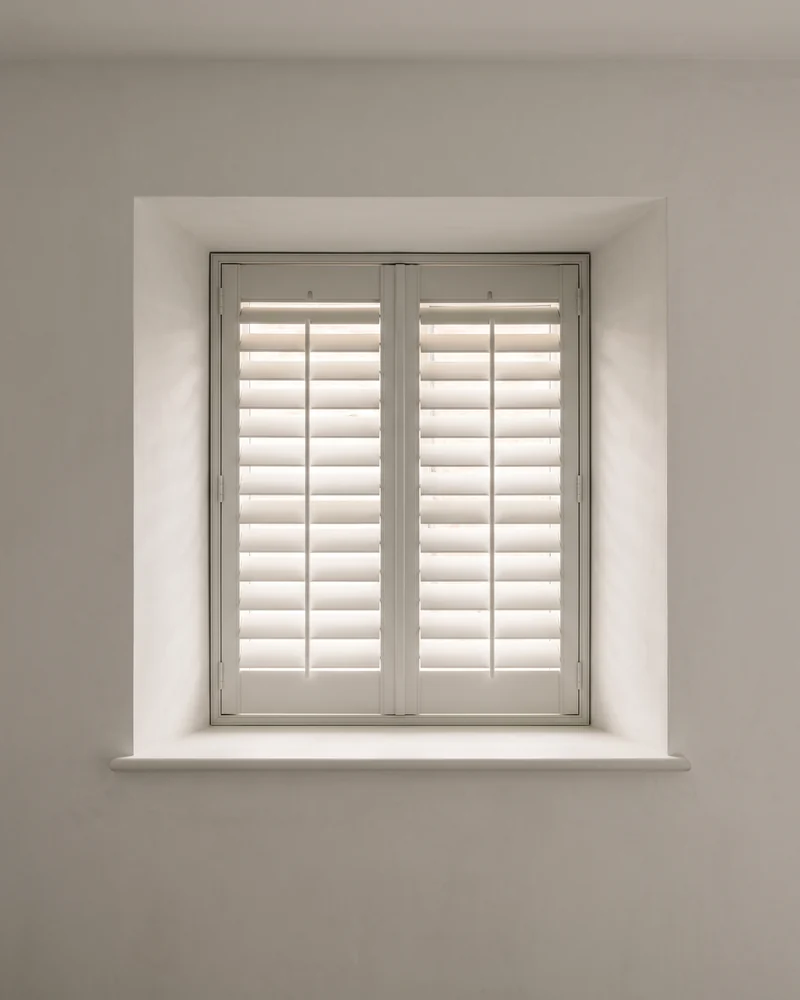 White polymer shutters fitted to an interior window