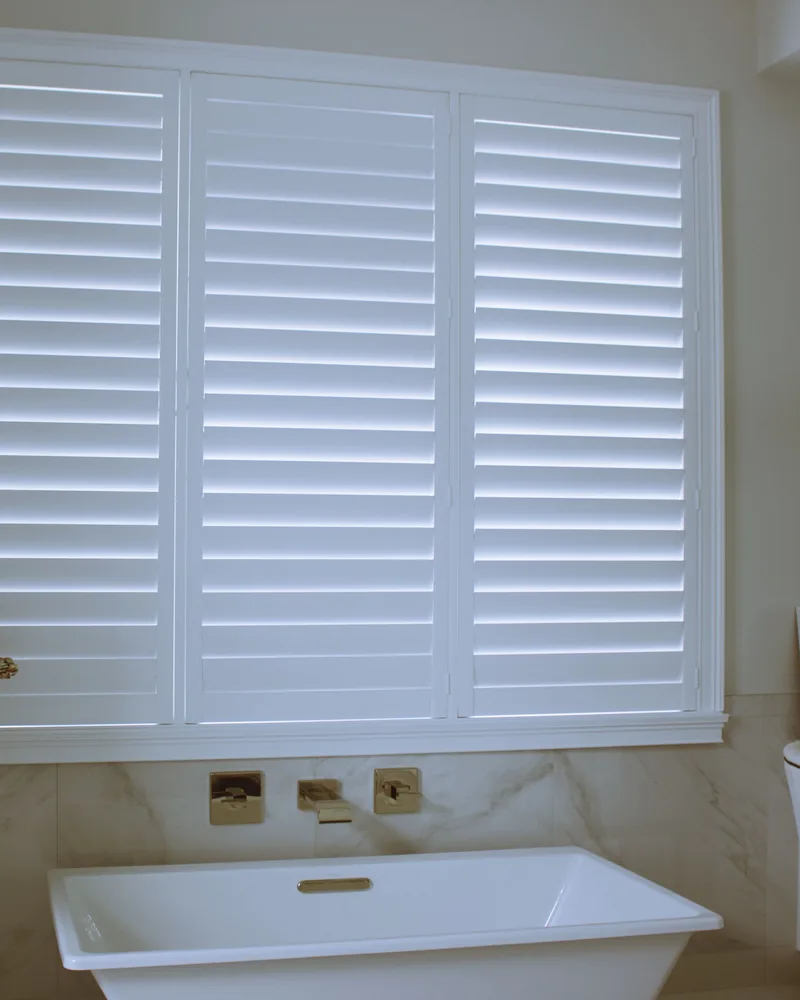 White shutters at a bathroom window above a bath