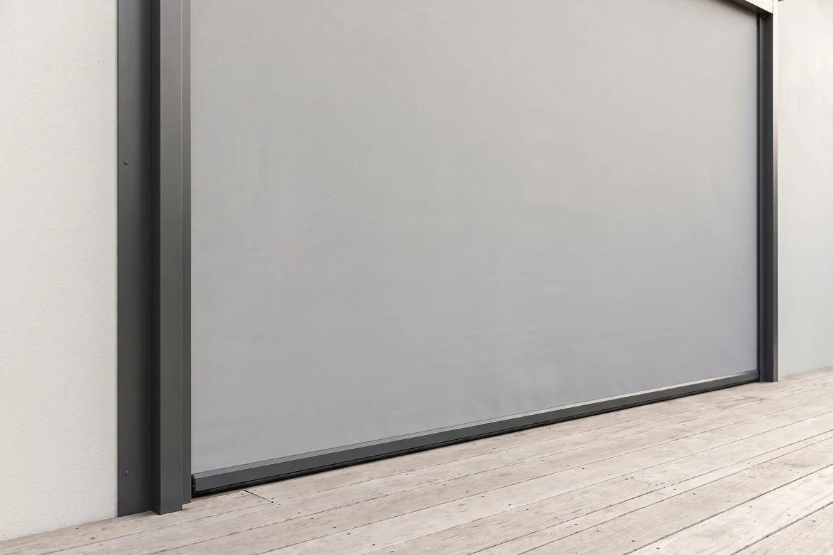 A track-guided outdoor blind lowered along the open side of an alfresco area