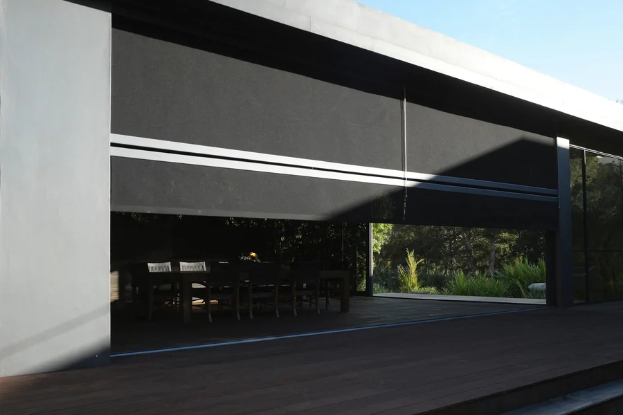 A track-guided outdoor blind sealing the side of an alfresco patio